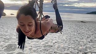 Shibari at sunset with Lari, her small tits and pussy exposed in the ropes.