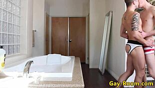 Tattooed gay twinks, one a bodybuilder, perform anal sex and facial in bathroom.