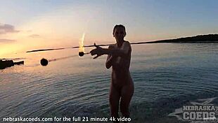 A pretty woman performs nude fire dancing on the beach at sunset.