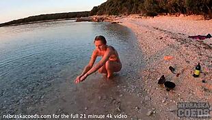 A pretty woman performs nude fire dancing on the beach at sunset.