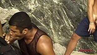 On the beach, two big hard dicked dudes mouth fuck a tanned twink.