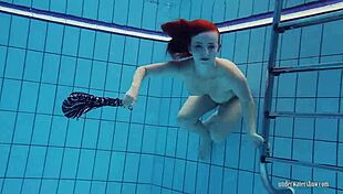 Lusty red head Katrin strips in underwater strip tease