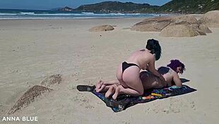 Two lesbians naked on the beach kissing passionately.