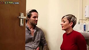 In the toilet, a busty tattooed milf jerks off a hard cock while talking dirty in a cfnm amateur scene