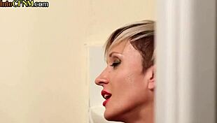 In the toilet, a busty tattooed milf jerks off a hard cock while talking dirty in a cfnm amateur scene