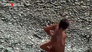 Na pláži horká holka ukazuje přirozený prsa a zadek se zátkou do zadku pro voyeury.