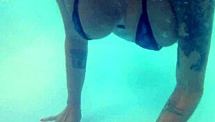 Melissa the mermaid swims in the pool with tattoos and brown eyes