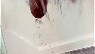 A muscular blonde bodybuilder with blue eyes showers her cock in the bath