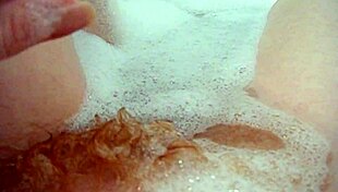 annie relaxes in the bath, fingering her hairy pussy