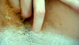 annie relaxes in the bath, fingering her hairy pussy