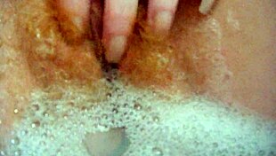annie relaxes in the bath, fingering her hairy pussy
