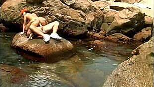 a mature man fucks an exotic babe in a cap and sunglasses on the seaside stones