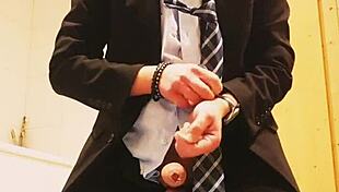 guy strokes his cock hard in tight business suit on bed