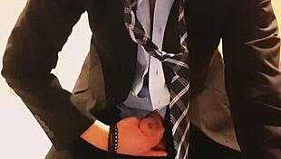 guy strokes his cock hard in tight business suit on bed