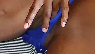 Slipping into bed wearing blue lingerie, she starts fingering her beautiful ebony curves gently