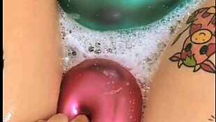 Tattooed girl teases balloons in steamy bath play